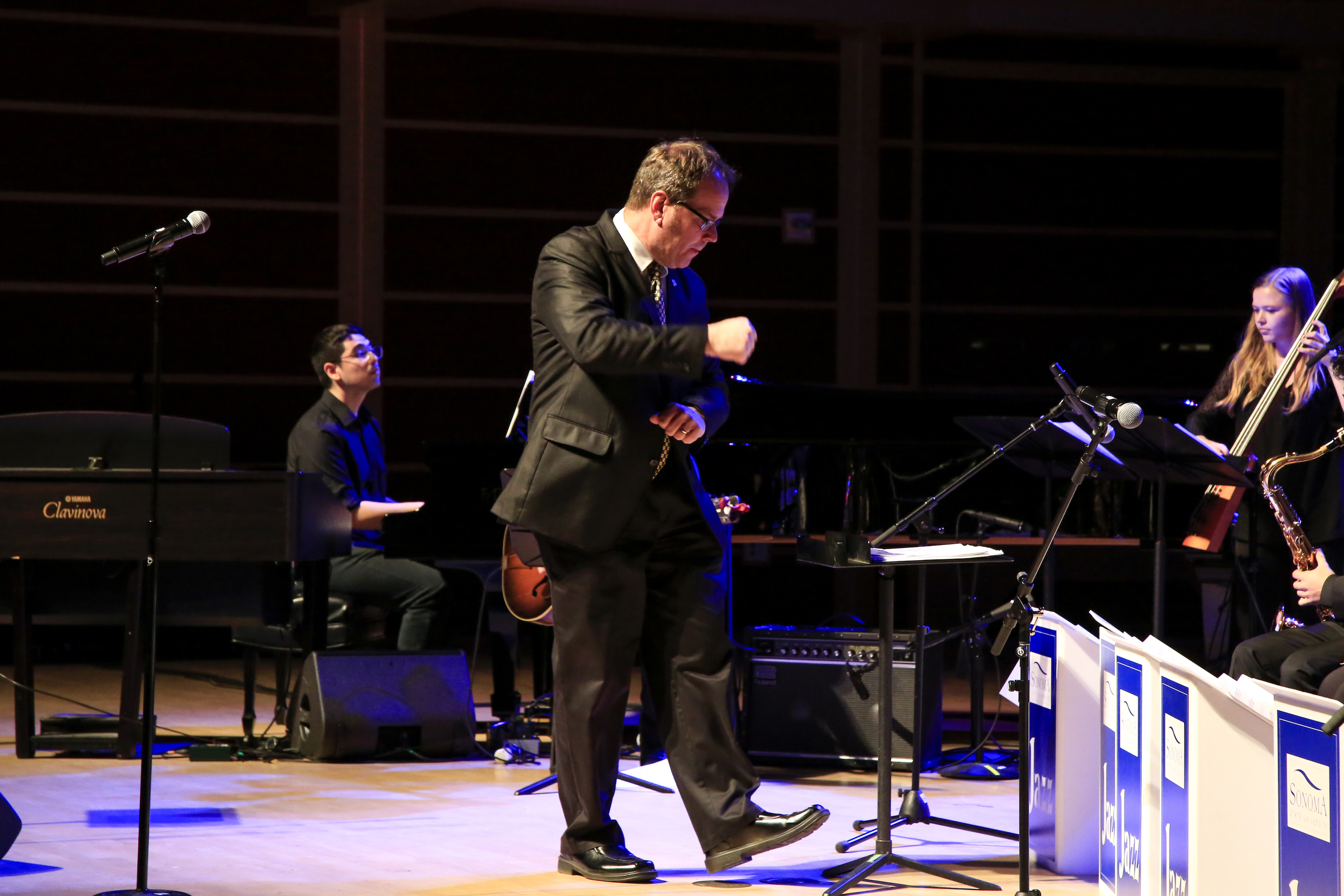 Doug conducting in front of a piano facing the jazz orchestra