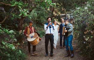 Saul Goodman's Klezmer Band holding instruments and walking through a forest
