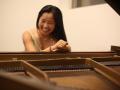 Leigh McAllister sitting and laughing behind a piano