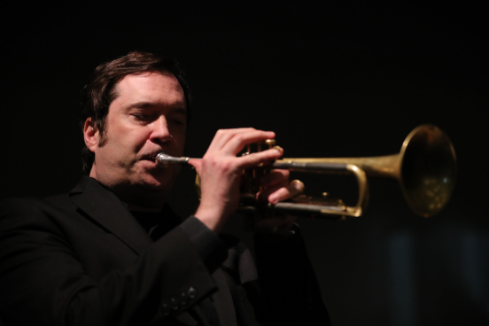 Ian Carey playing trumpet and dressed in black