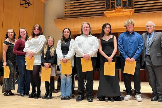Students holding papers on stage of Schroeder Hall