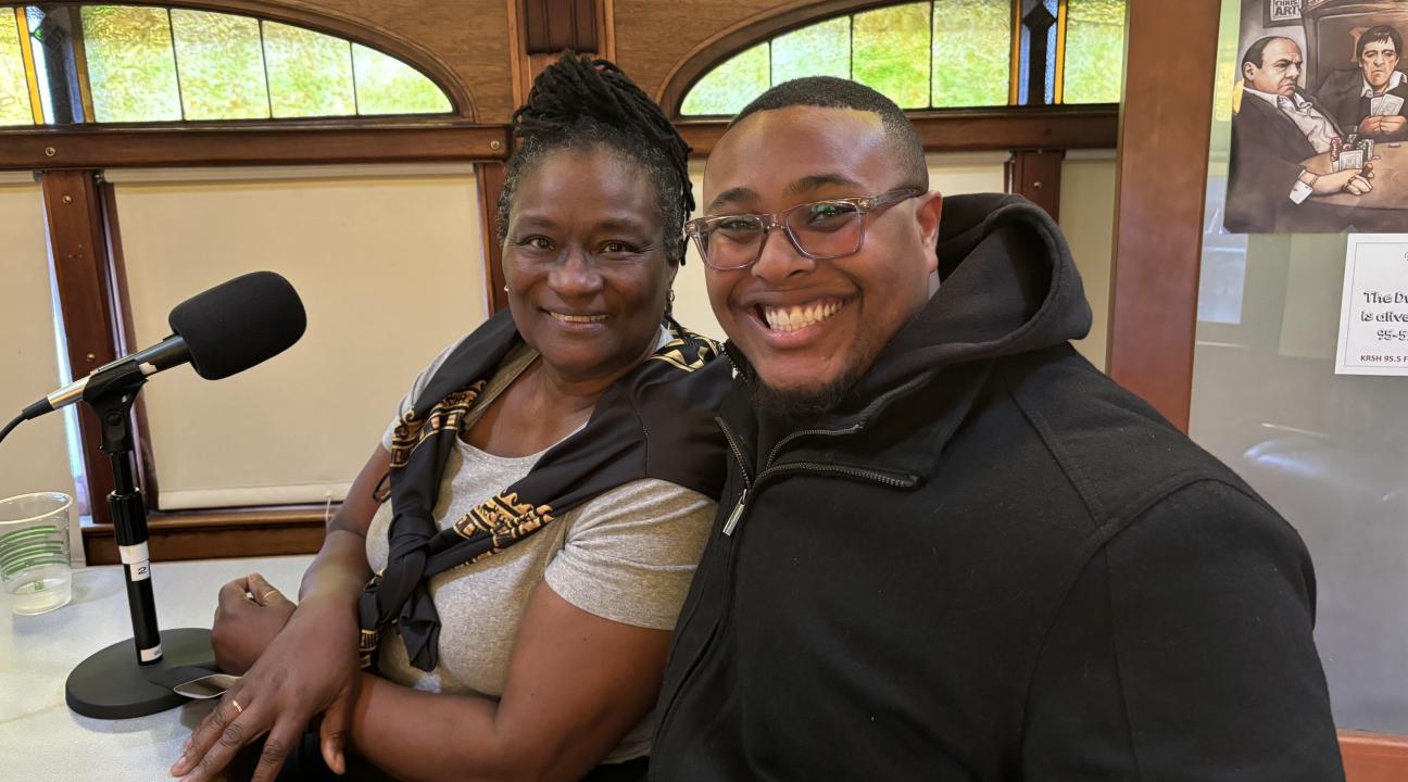 Lynne Morrow and Malik-Charles D. Wade I smiling while sitting in front of a microphone