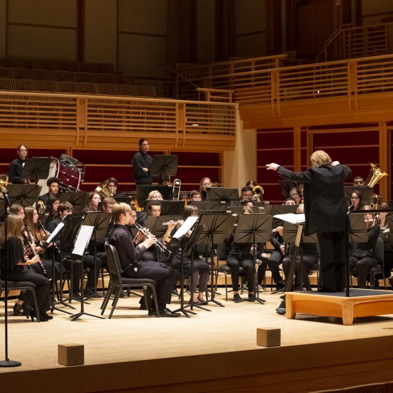 wind band on stage performing with Dr. Kim Mieder conducting