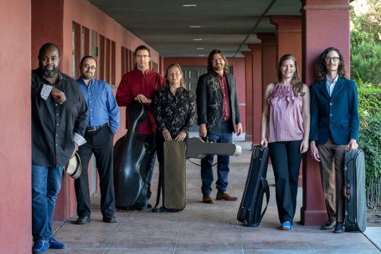 people with instruments in cases standing in an outdoor corridor