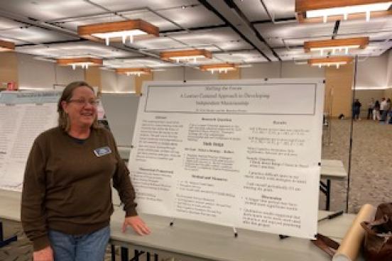 Dr Mieder standing in front of a poster board on a table in the student center ballroom
