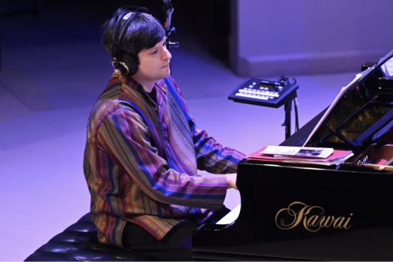 Noam Lemish playing at the piano with headphones on