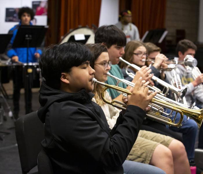 Row of student trumpet players sitting and practicing