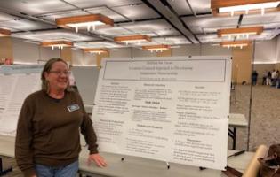 Dr Mieder standing next to a poster board on a table in the student center ballroom