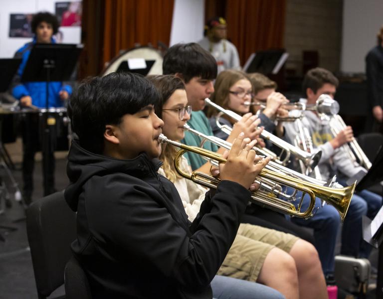 Row of student trumpet players sitting and practicing