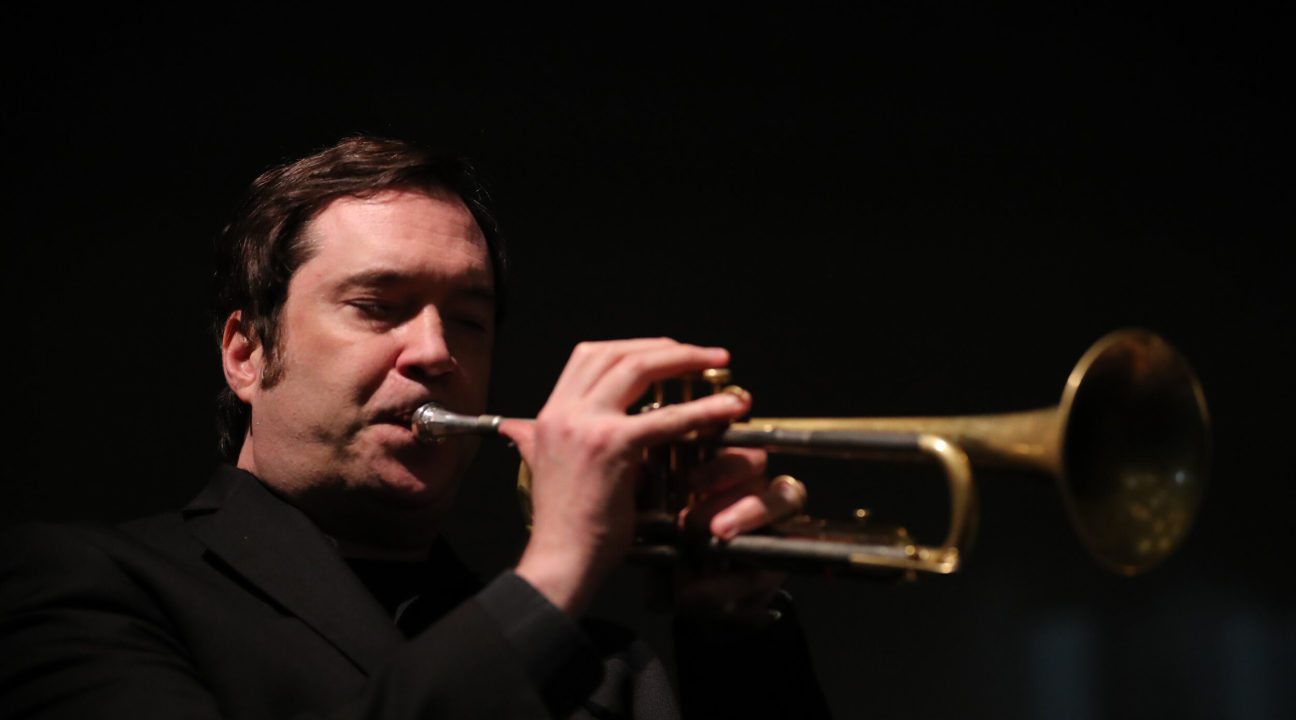 Ian Carey playing trumpet and dressed in black