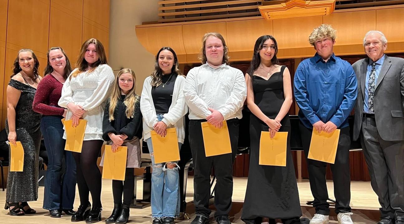 Students holding papers on stage of Schroeder Hall