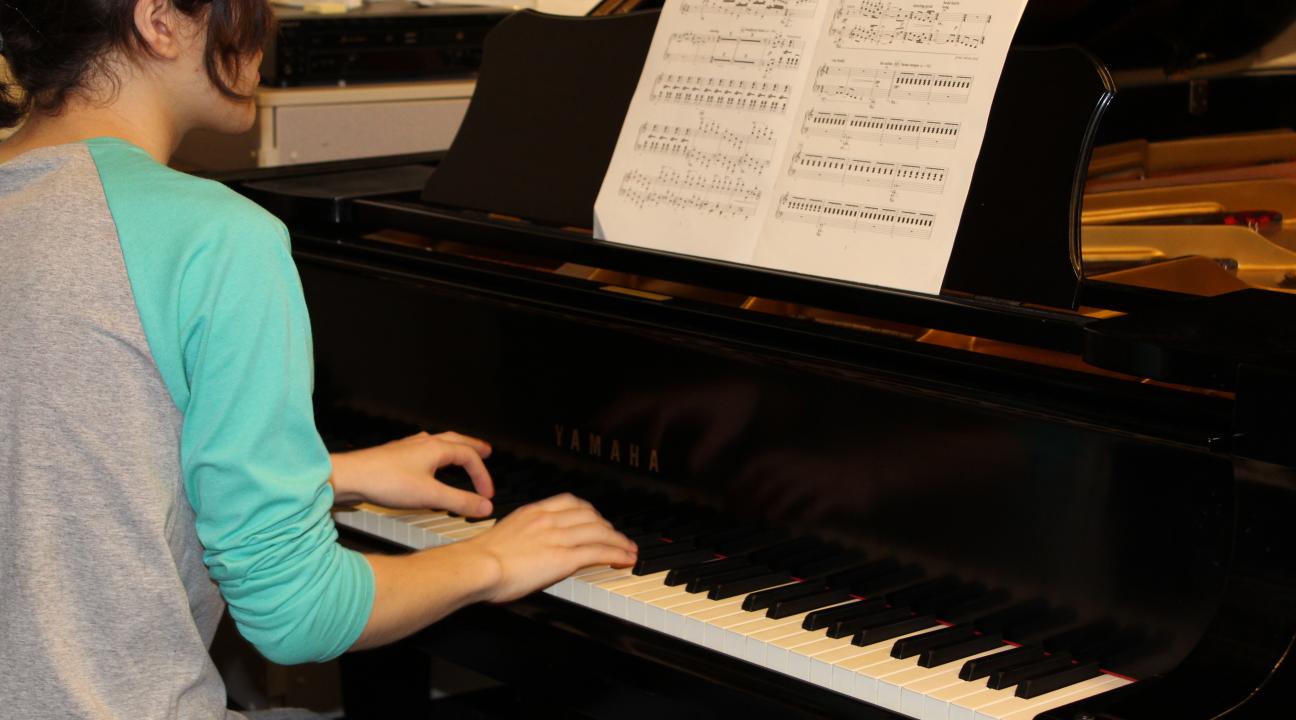 student sitting at piano ready to play