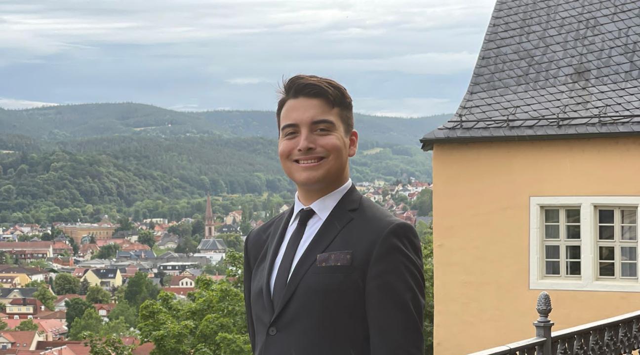 Jack Adkins standing in a suit near railing outdoors