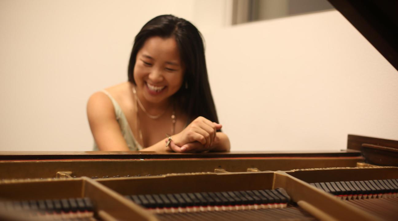 Leigh McAllister laughing behind a piano