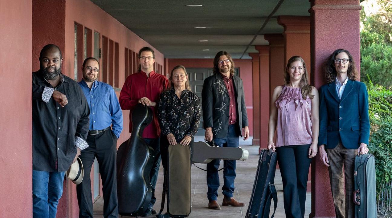 people with instruments in cases standing in an outdoor corridor