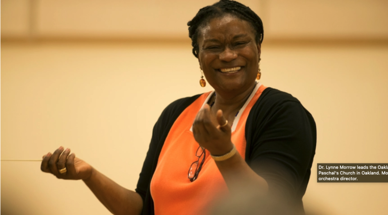 Lynne holding up her hands with baton and smilig 