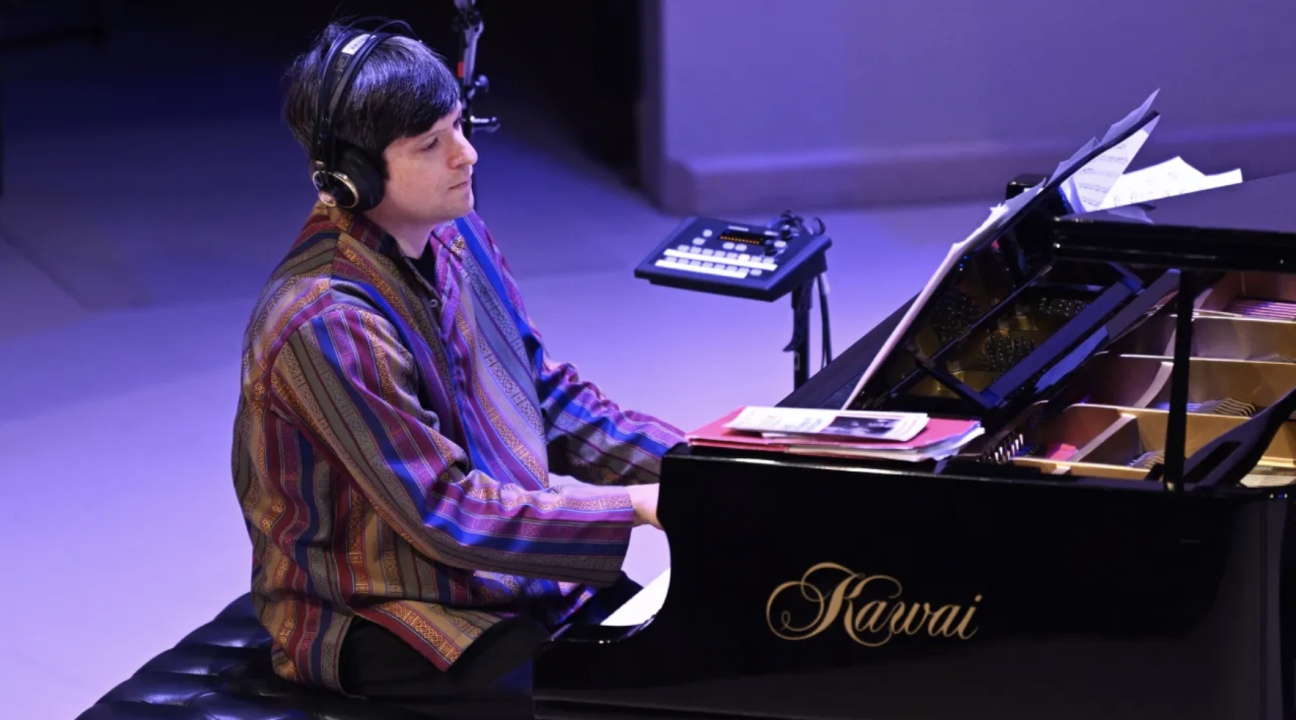 Noam Lemish playing at the piano with headphones on