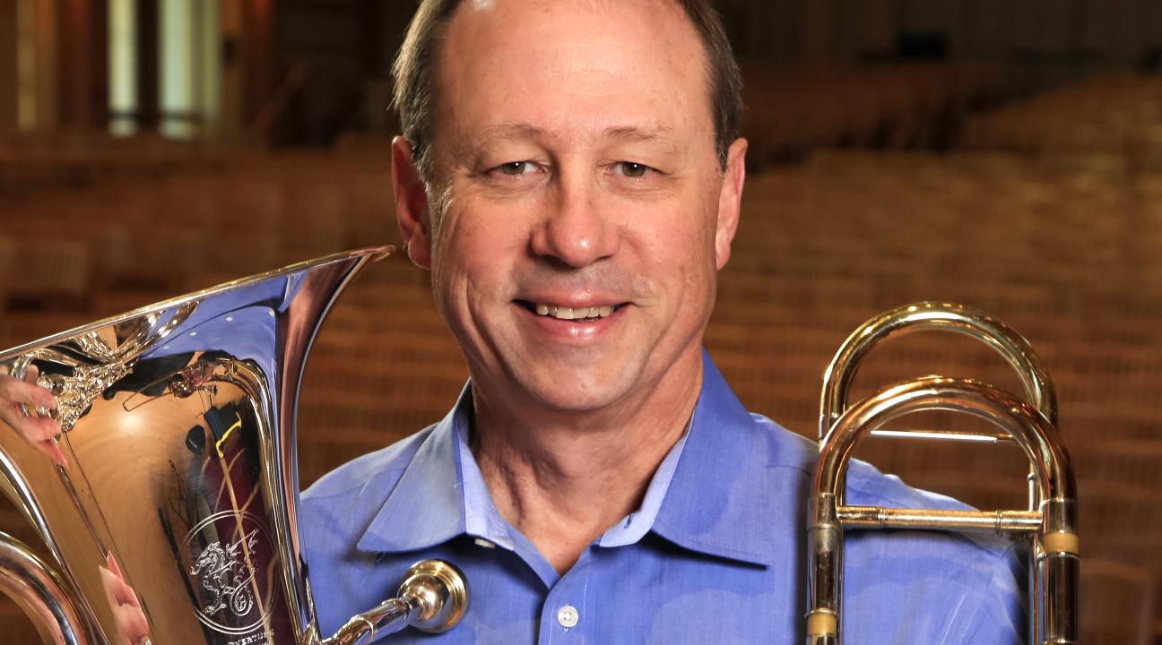 Tony Collins Headshot with trombone and ehuphonium