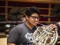 A college student plays the musical instrument, the French horn, during symphony rehearsal