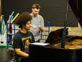 Jomei Greer practicing at piano with instructor behind