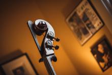 arty photograph of the top of a cello with some soft focus art in the background
