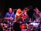 Jeanne Geiger on stage playing trombone with drummers behind her