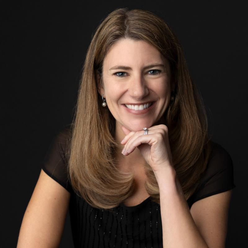 Jenny Bent headshot with dark background and her head resting on one of her hands