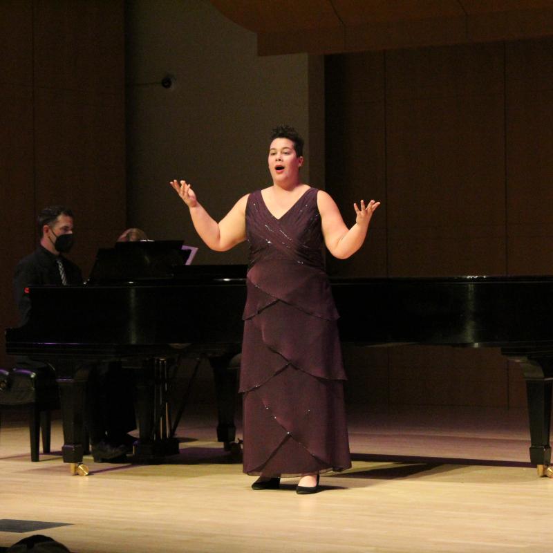 Alfie Halpern singing in front of a piano on Schroeder stage