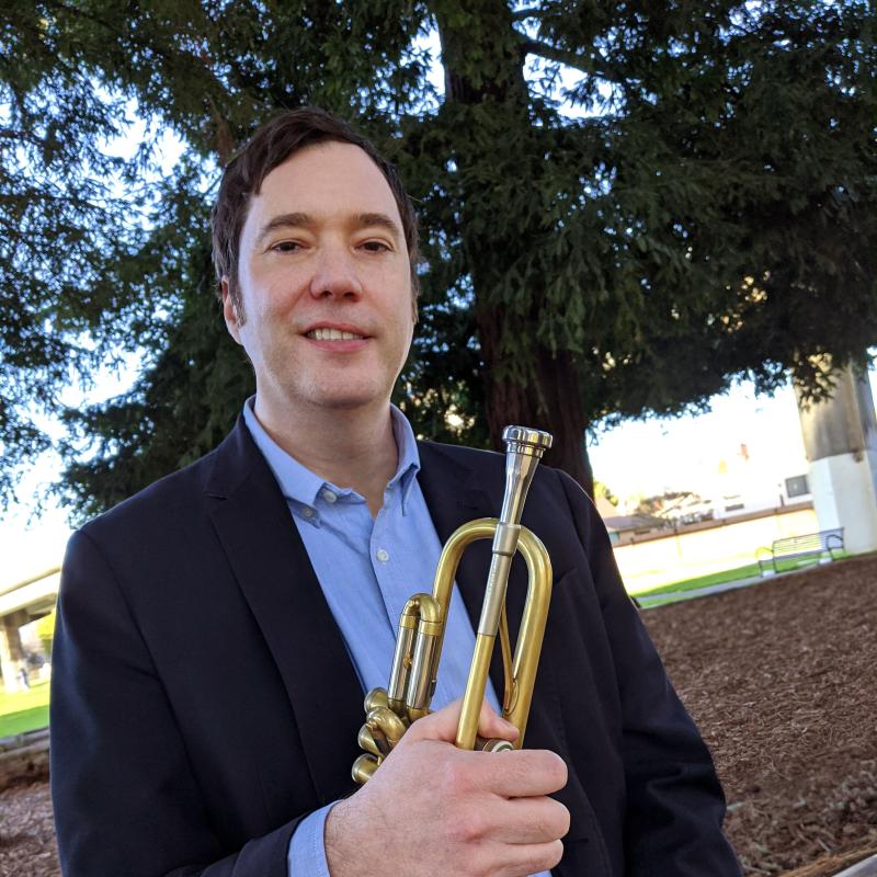 Ian Carey headshot holding trumpet