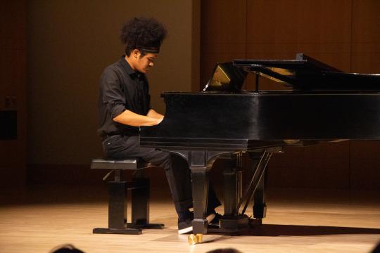 Jomei Greer sitting and playing at the piano