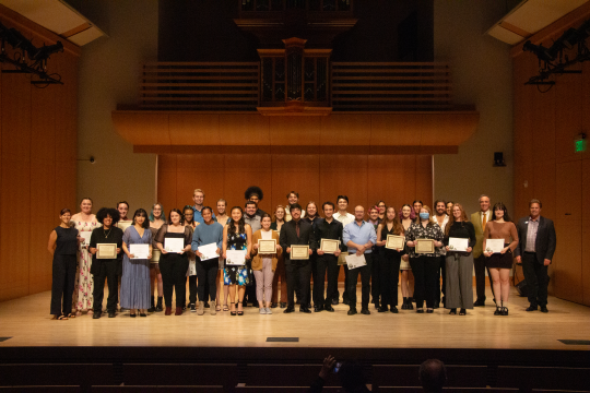 Scholarship recipients with certificates on stage for group picture