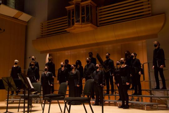 SonoVoce standing on choral risers and singing on Schroeder stage