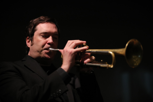 Ian Carey playing trumpet and dressed in black