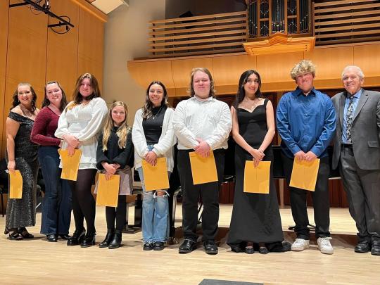 Students holding papers on stage of Schroeder Hall