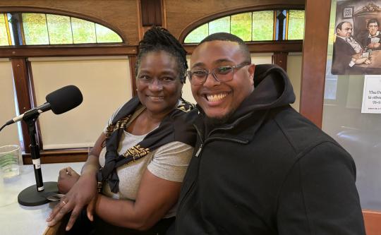 Lynne Morrow and Malik-Charles D. Wade I smiling while sitting in front of a microphone