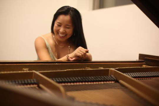 Leigh McAllister laughing behind a piano