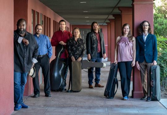 people with instruments in cases standing in an outdoor corridor