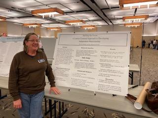 Dr Mieder standing in front of a poster board on a table in the student center ballroom