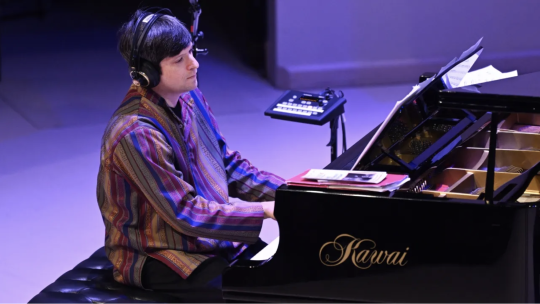 Noam Lemish playing at the piano with headphones on