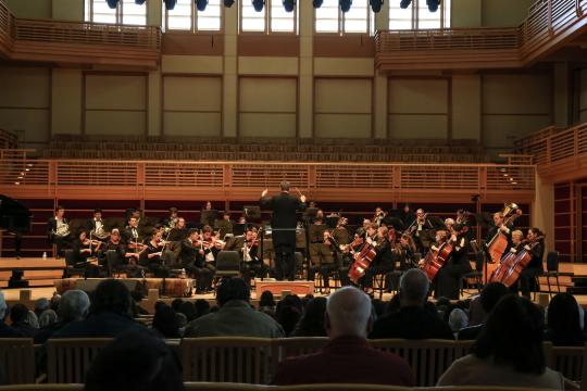 The orchestra performing on stage with an audience in the foreground