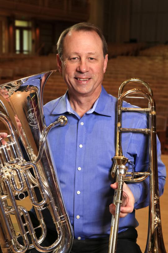 Tony Collins Headshot with trombone and ehuphonium