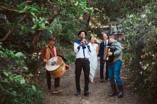 Saul Goodman's Klezmer Band holding instruments and walking through a forest