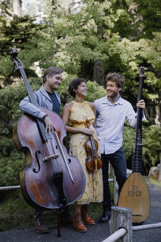 Beneath A Tree ensemble standing with instruments in front of trees