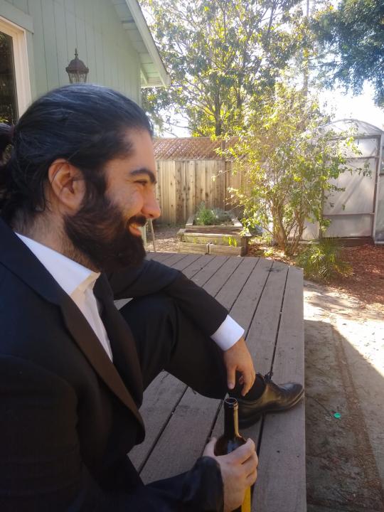 Michael Coury Murdock sitting outside on a deck holding a bottle