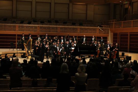 Orchestra stands at applause with soloist Nick Maritz in front of the piano