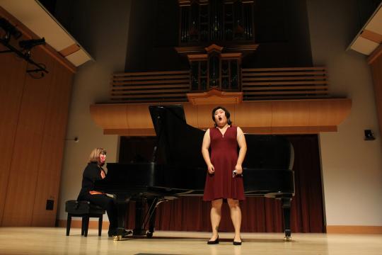 Singer singing on Schroeder stage with accompanist