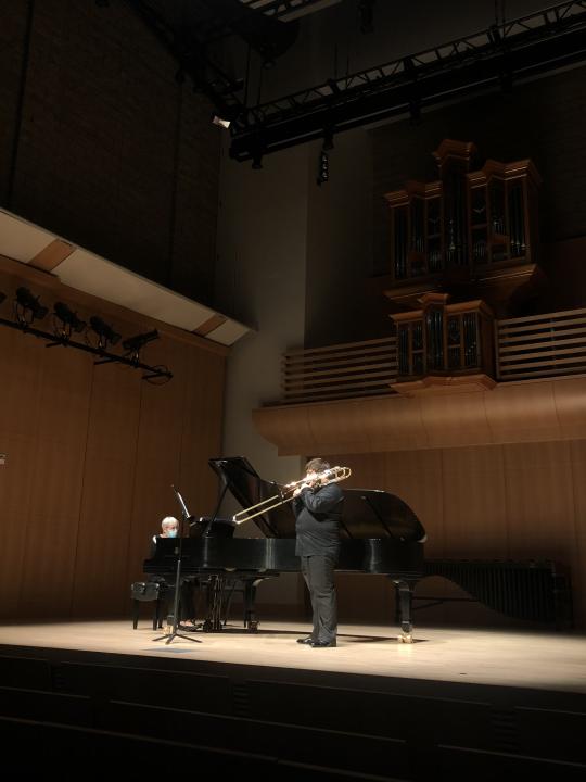 Trombonist performing with piano on stage