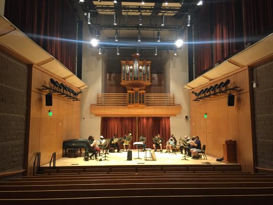 Brass ensemble performing on stage of Schroeder Hall with bright lights