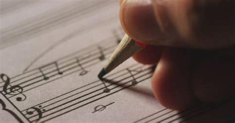 Hand holding pencil and writing a music score