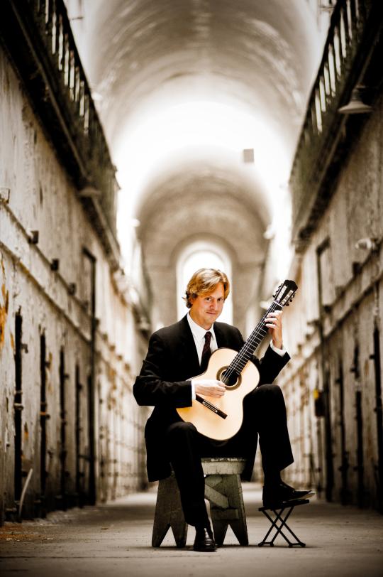 Jason Vieaux with guitar in corridor